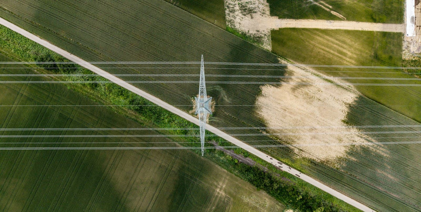 Aerial view of a wind turbine beside power lines across farmland