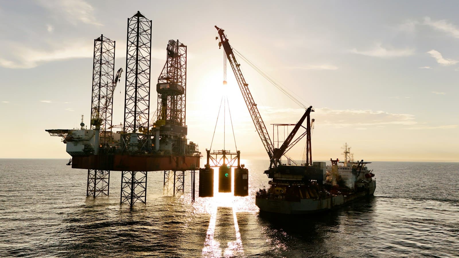 A jack-up oil rig serviced by a supply vessel at sea